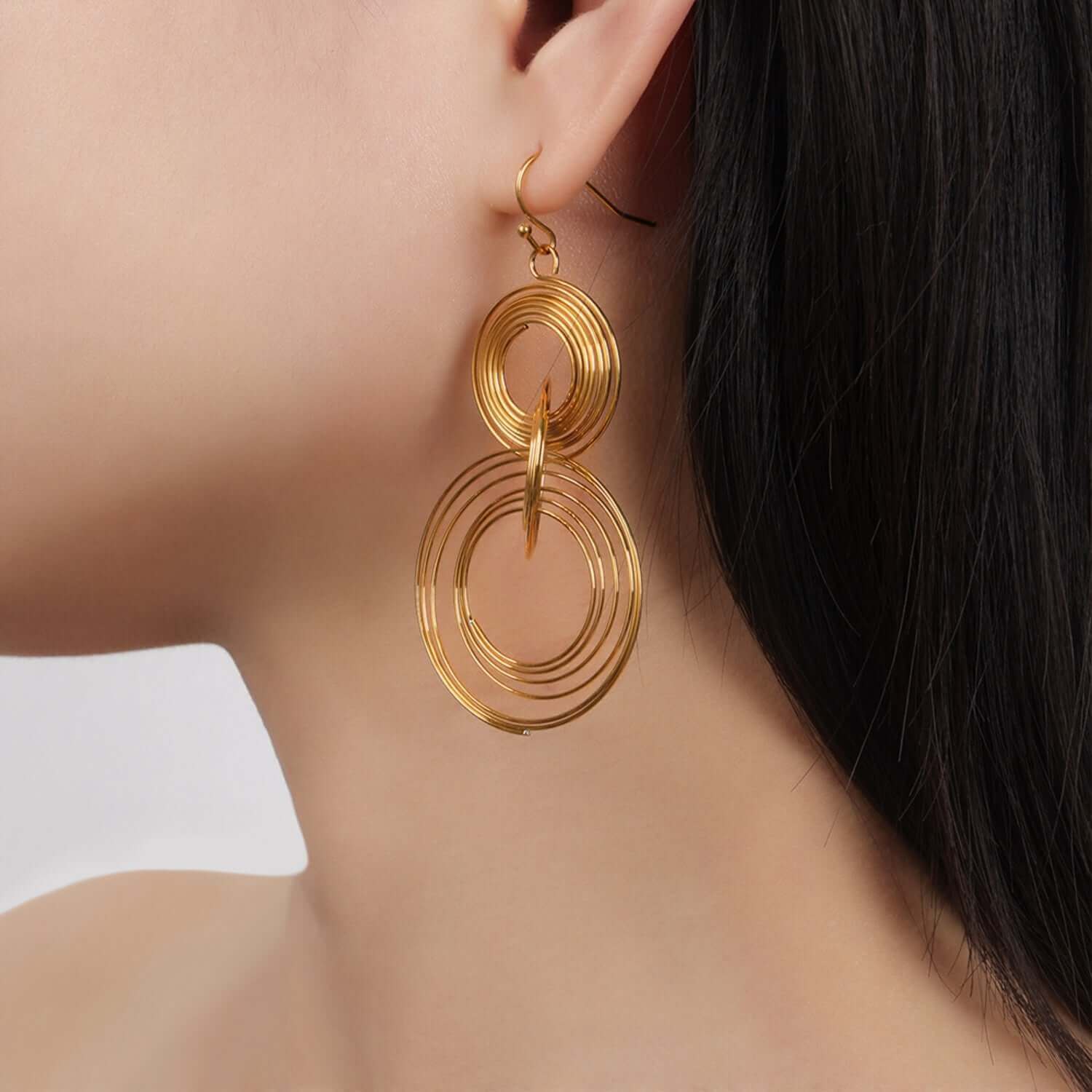 Titanium steel gold-plated multi-layered round shape earrings on model's ear, 2.7 inches in length, weighing 0.2 oz (6 g).