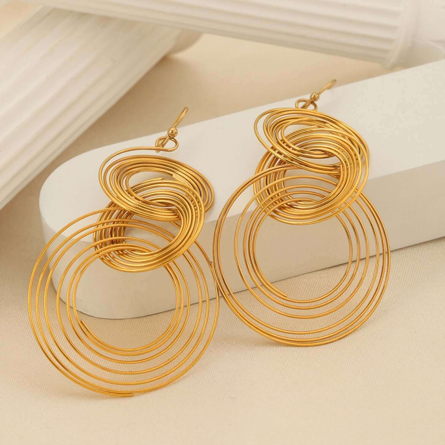 Gold-plated titanium steel multi-layered round shape earrings on a beige surface