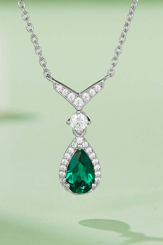 Sterling silver teardrop necklace with lab-grown emerald and zircon on green background, modern style jewelry.