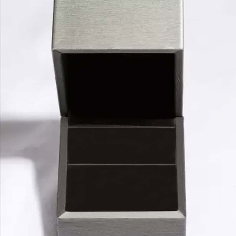 Open silver jewelry box with black interior, perfect for showcasing rings or small accessories.