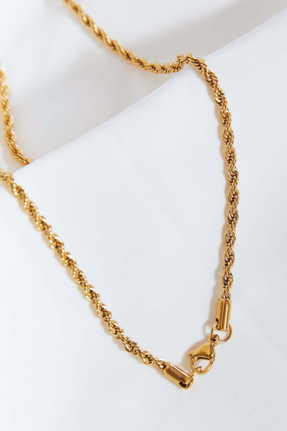 Brass twisted chain lightning pendant necklace with cubic zirconia detail, crafted from brass and stainless steel, flat lay display.