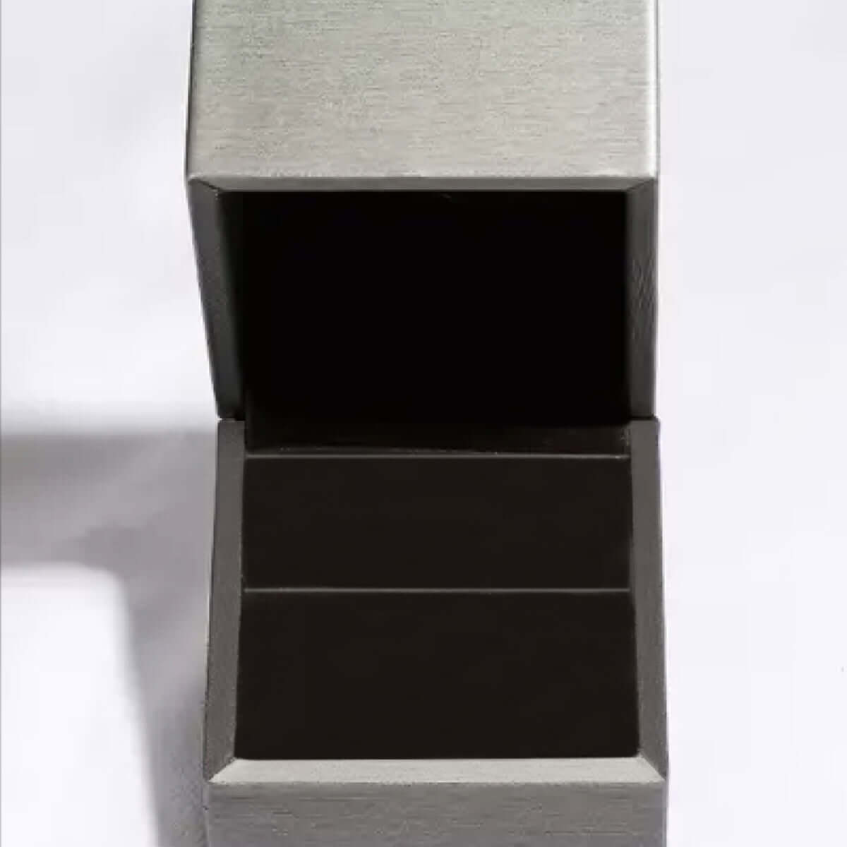 Empty silver jewelry box with open lid, displaying a velvet interior, designed for rings or small accessories.