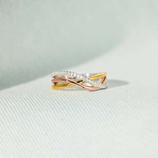 Crisscross gold-plated 925 sterling silver ring with rose gold accents, showcasing elegant design on a soft fabric background.