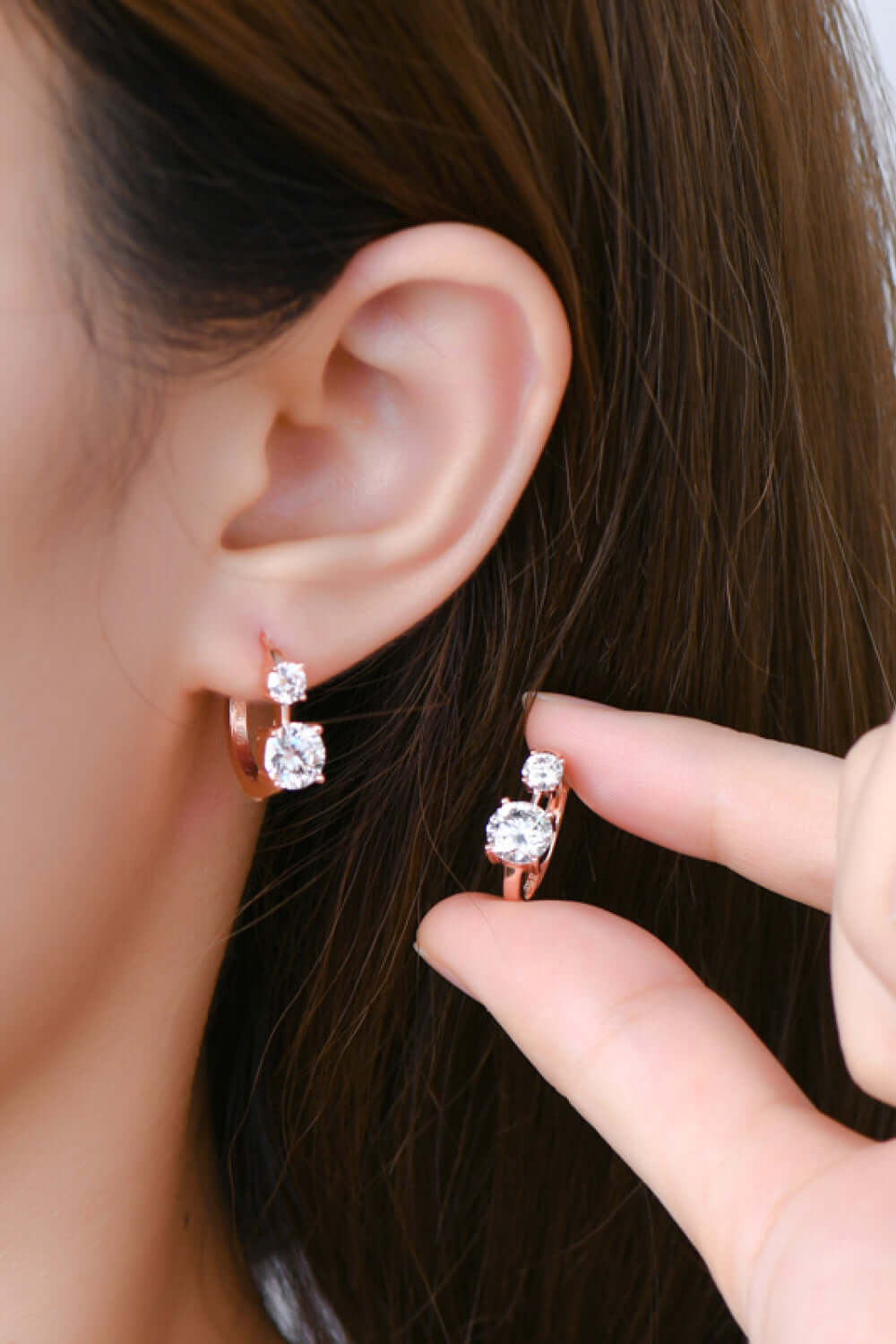 Moissanite earrings in 925 sterling silver with 18K rose gold plating worn on ear, showcasing elegant design and brilliance.