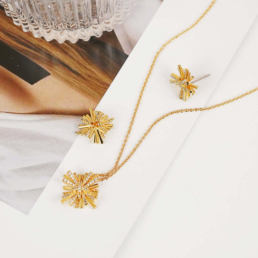 Starburst gold-plated necklace and earrings set with zircon detailing on a white background.