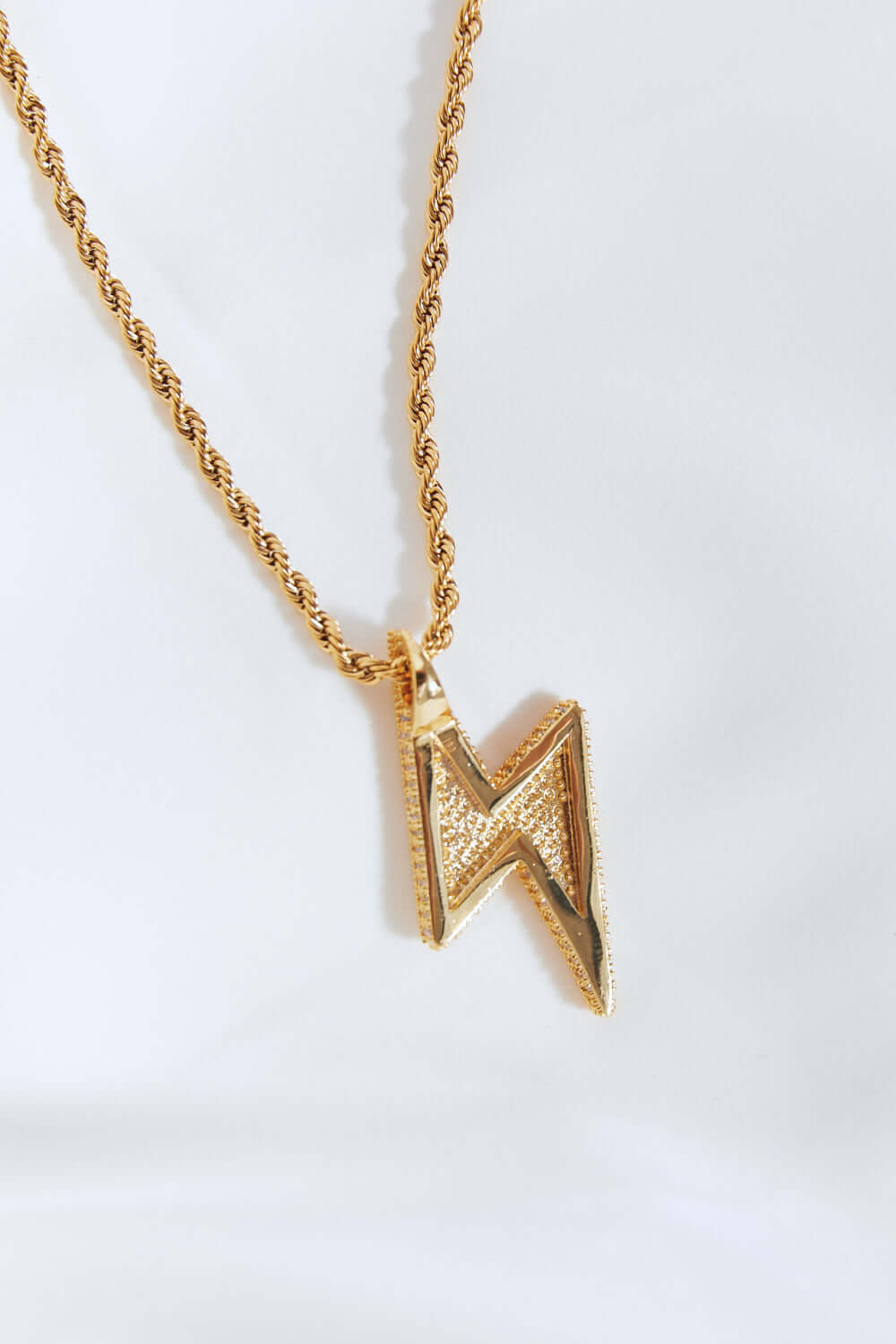 Brass Lightning Pendant Necklace with Twisted Chain and Cubic Zirconia Detail in Flat Lay Style