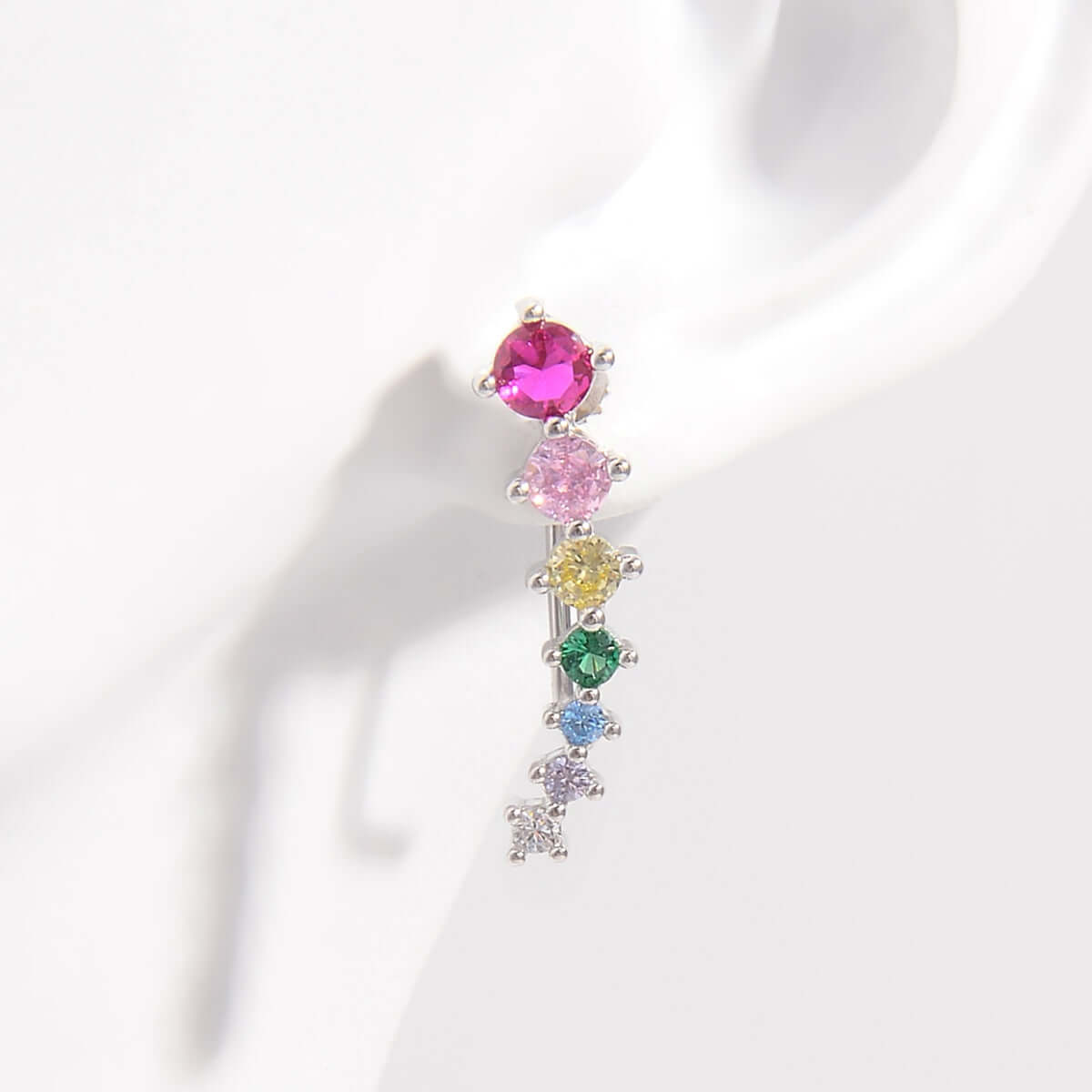 Multi-colored zircon drop earring on ear, featuring a platinum-plated, 925 sterling silver design with rainbow stones.