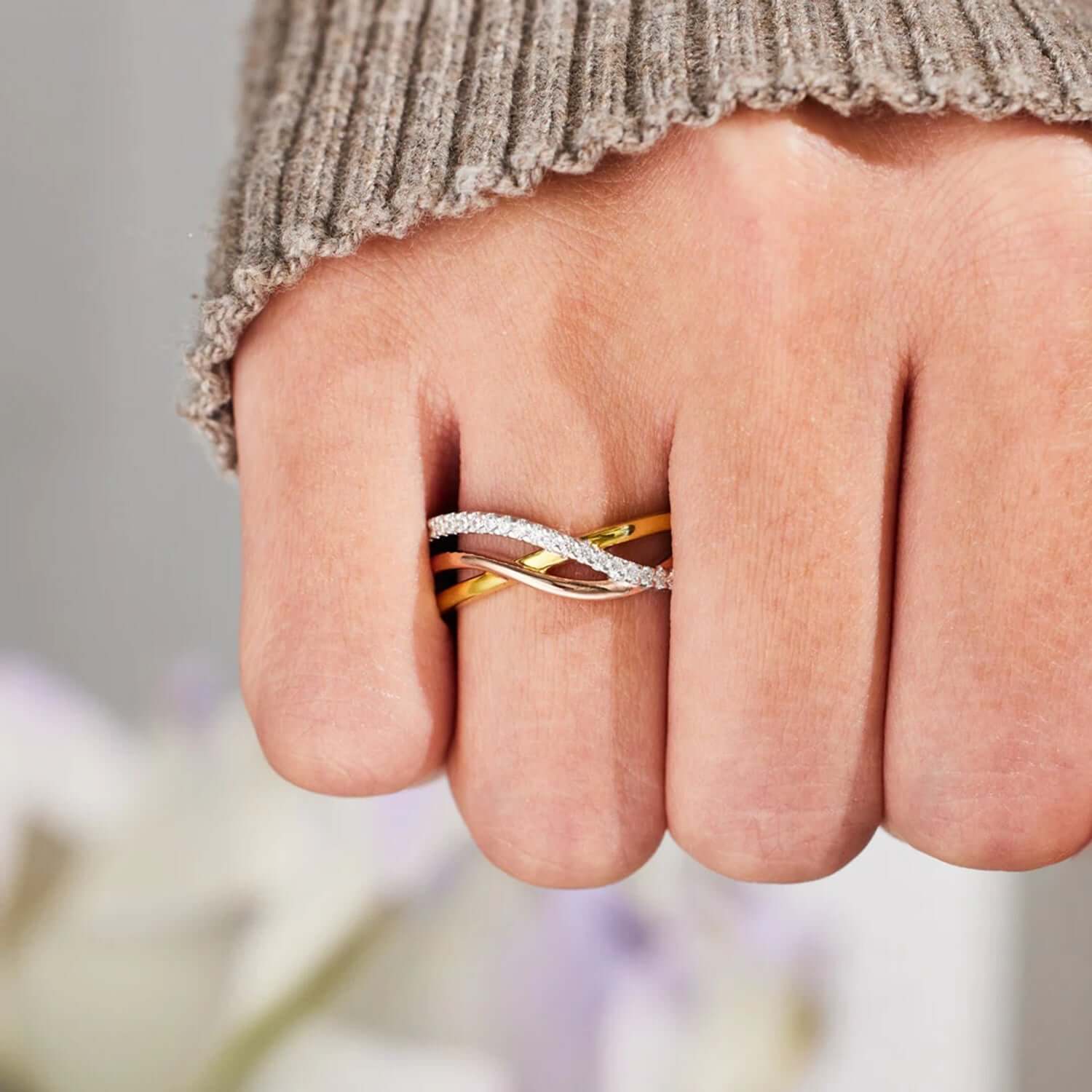 Crisscross gold-plated 925 sterling silver ring on hand, featuring elegant rose gold accents and intricate design.