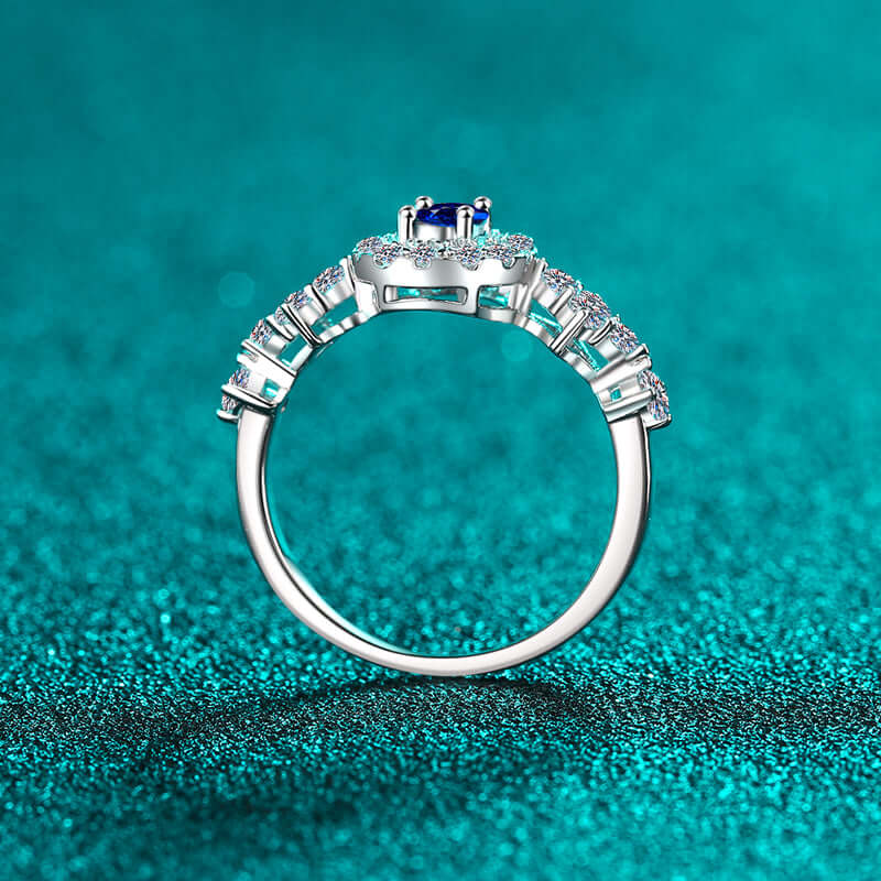 "925 sterling silver moissanite ring with 0.5 carat stone on teal background, showcasing intricate band details"