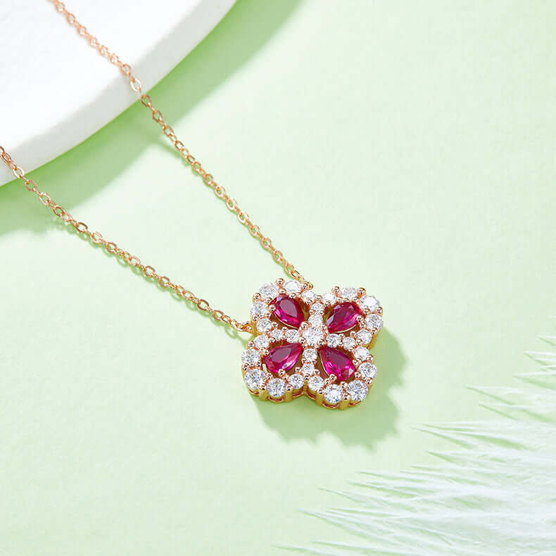 Lab-grown ruby flower-shaped necklace in 925 sterling silver with 18K rose gold plating on a green background.