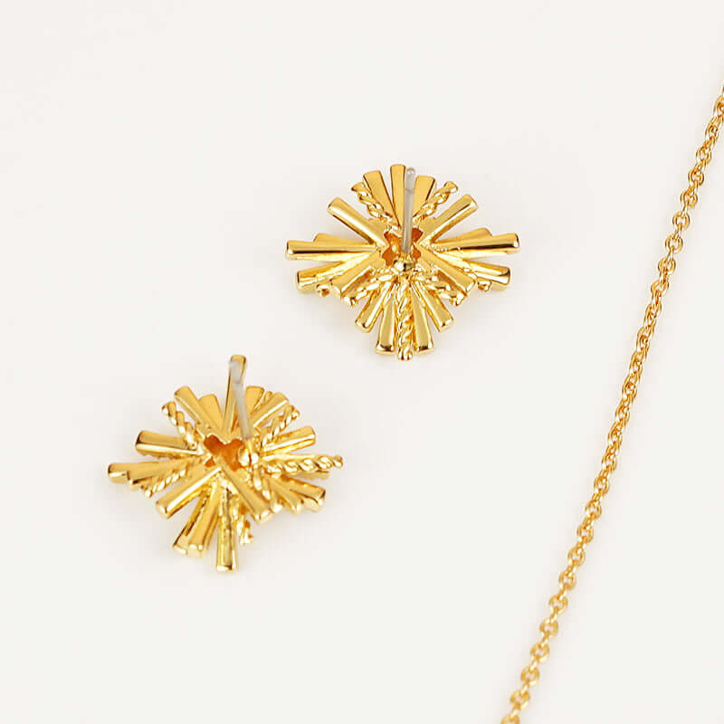 Gold-plated starburst earrings and necklace set with intricate zircon design against a white background.