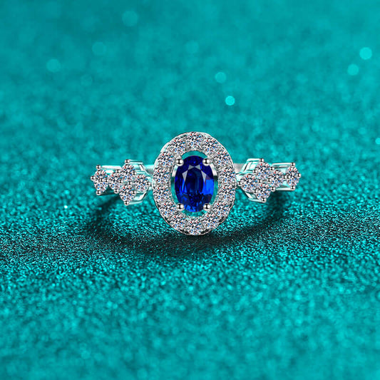 Elegant 925 sterling silver ring with a vibrant blue gemstone on a glittery teal background.