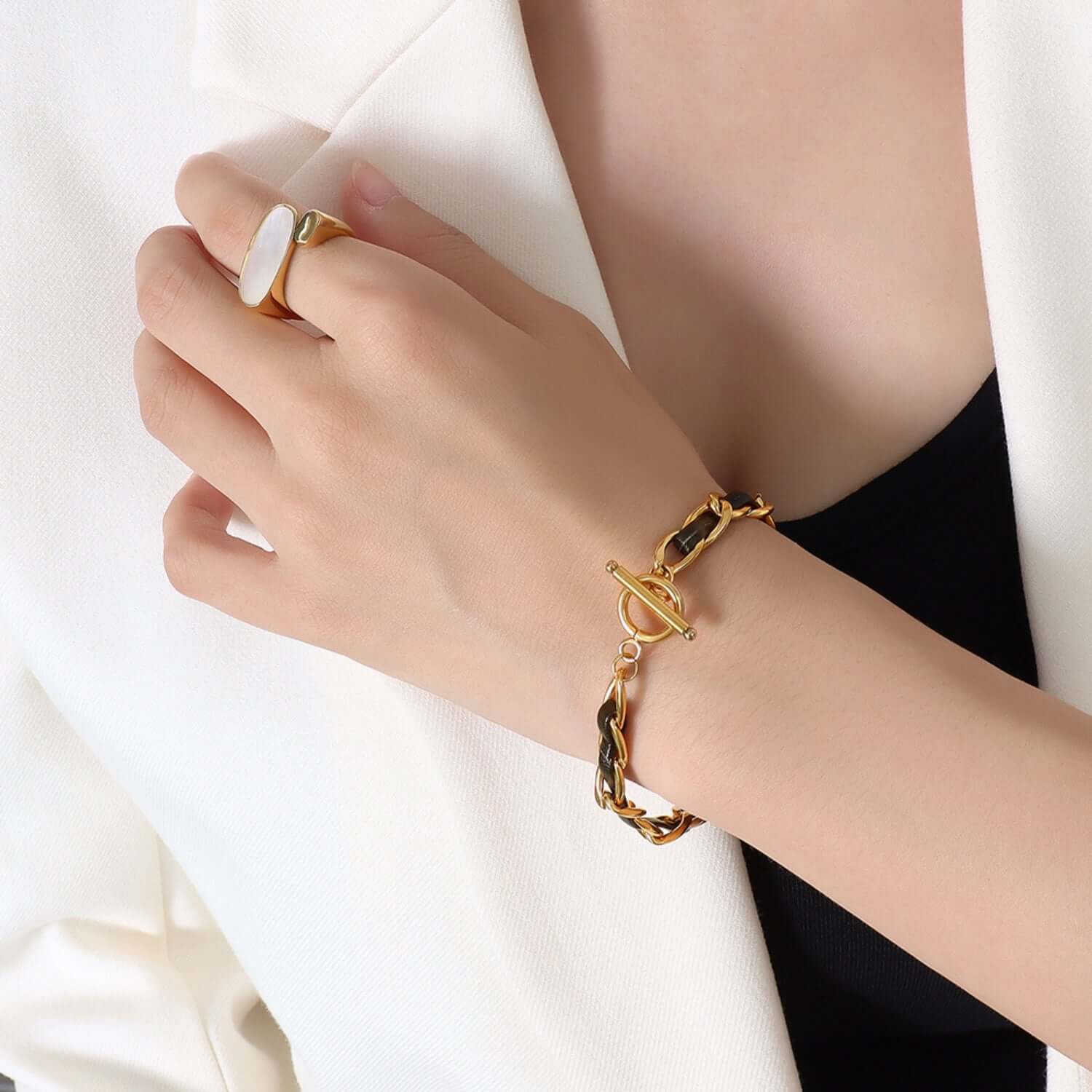 Elegant 18K gold-plated leather chain bracelet on wrist with white blazer background.