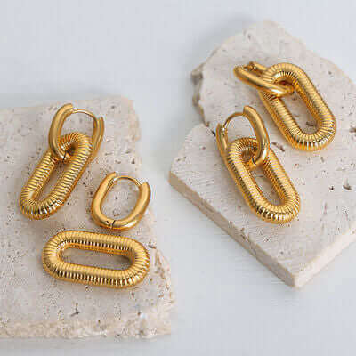 Gold-plated titanium steel dangle earrings displayed on white stone tiles